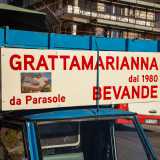 Subito risalta agli occhi il suo Ape azzurro, su cui sono apposte le scritte che riportano i nomi di �Grattamarianna� e �Parasole�